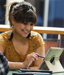 College student, sitting at a table viewing information on a tablet