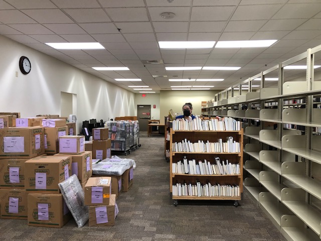 Library staff move books off shelves next to boxes